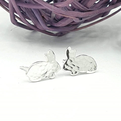 Silver earrings of a sideways facing rabbit with a hammered texture