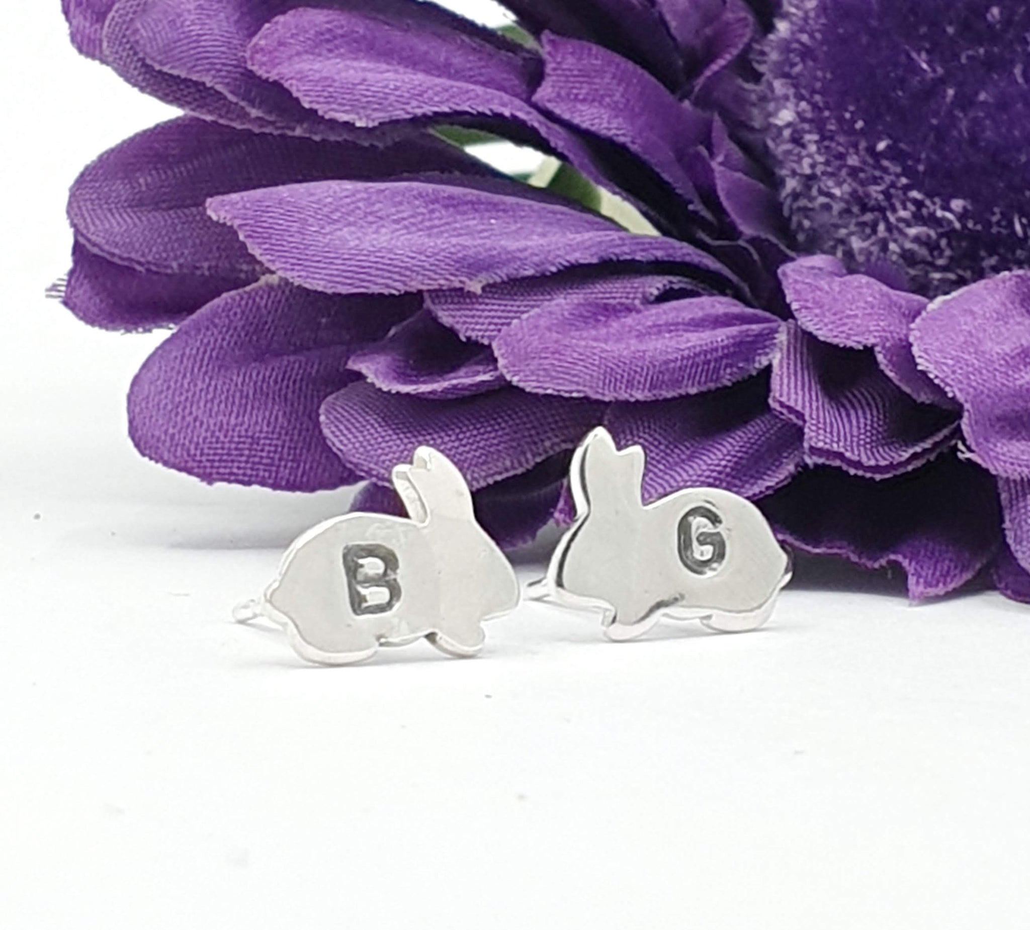 Silver earrings of a bunny sideways with the initial B and G on engraved on each earring 