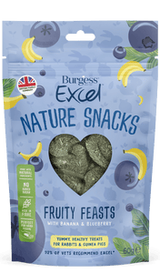 The packet for burgess excel fruity feast nature snacks is light blue with cartoon images of bananas and blueberries. A heart shaped clear window in the centre shows the heart shaped treats within. A green box to the left of the packet highlights the benefits, nature ingredients, no added sugar, high in fibre and perfect for hand feeding. Treats for rabbits and guinea pigs recommended by 92% of vets.