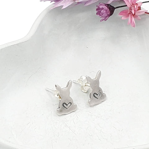 Silver stud earrings in the shape of a rabbit with a love heart engraved in the middle.