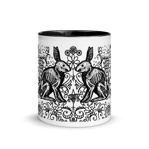 ceramic halloween mug. Two black bunny rabbit silhouettes with their skeletons visible, on a field of elaborate, black, floral swirls on a white background.